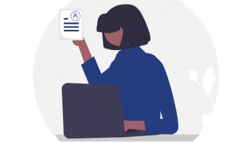 woman in front of computer, holding paper with A grade